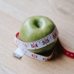 A weight loss-themed green apple with a measuring tape around it.