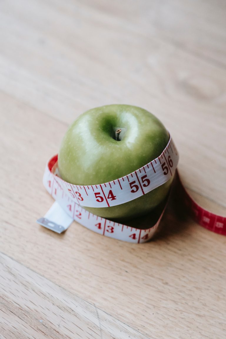 A weight loss-themed green apple with a measuring tape around it.