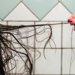 A woman is blow-drying her oily hair.
