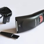 A hair clipper and hair brush in close up for Men's Hair Care.